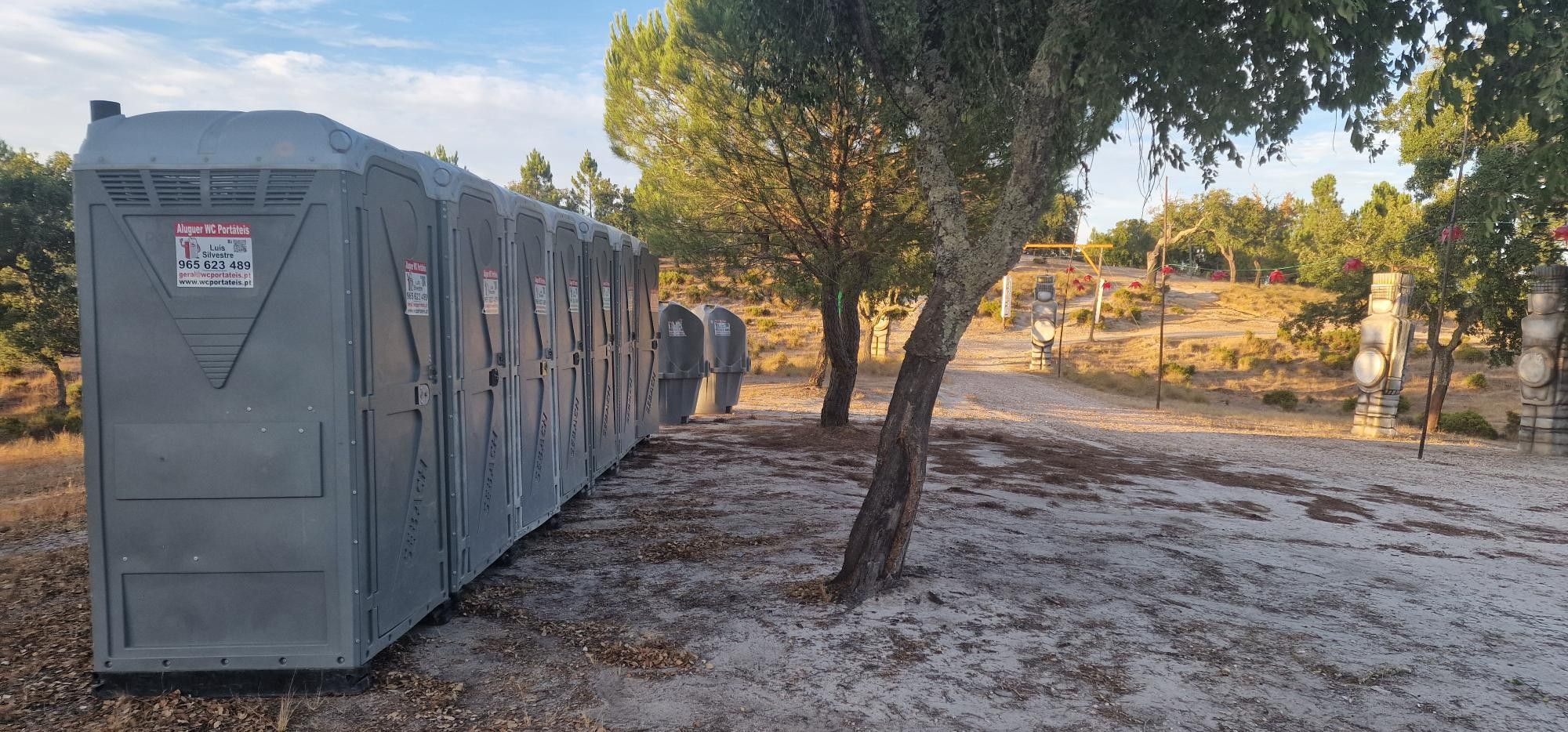 WC portáteis cinzentos e urinóis instalados num pinhal