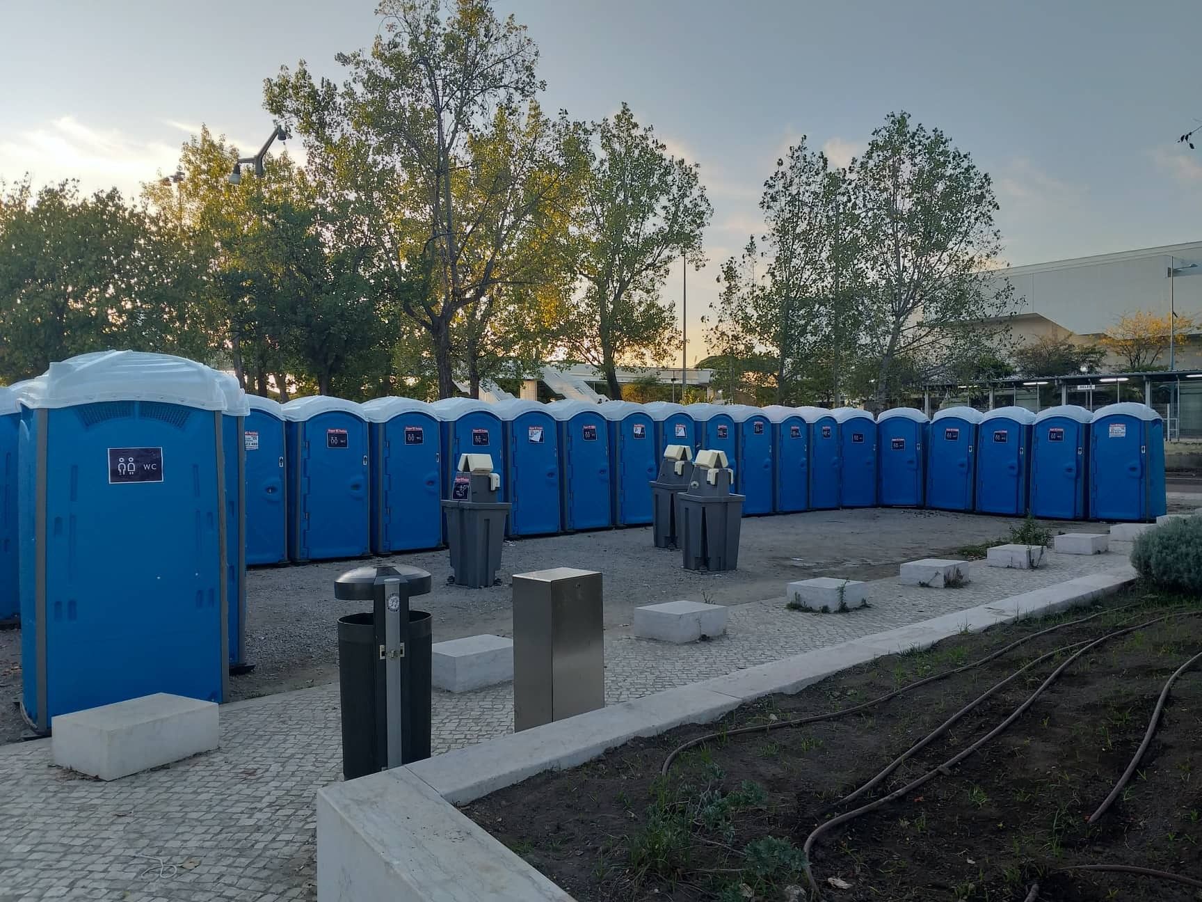 Recinto de evento com mais de vinte WC portáteis azuis e estações lava-mãos