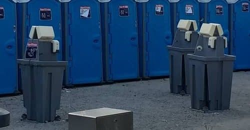 Três estações lava-mãos entre filas de WC portáteis azuis