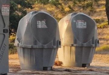 Dois urinóis portáteis de quatro postos num recinto ao ar livre