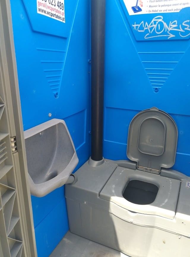Interior de um WC portátil azul com sanita e urinol